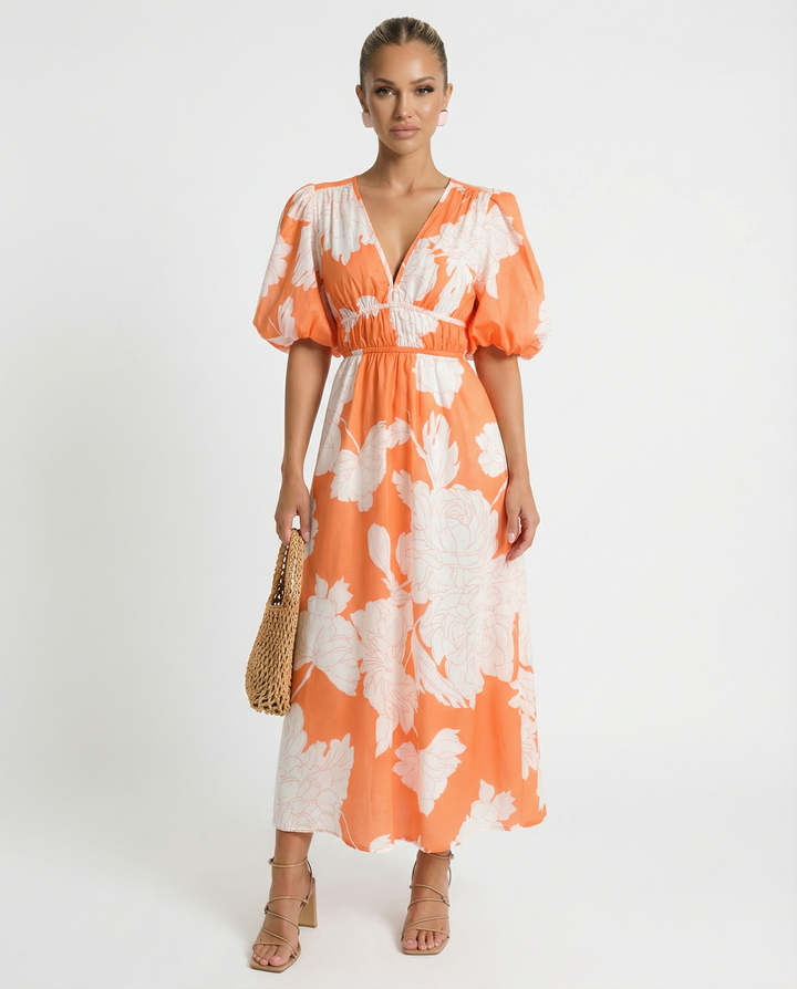 Woman wearing an orange floral midi dress with a relaxed silhouette on a plain background