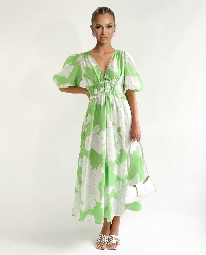 Woman wearing a floral midi dress with short puff sleeves on a plain background.