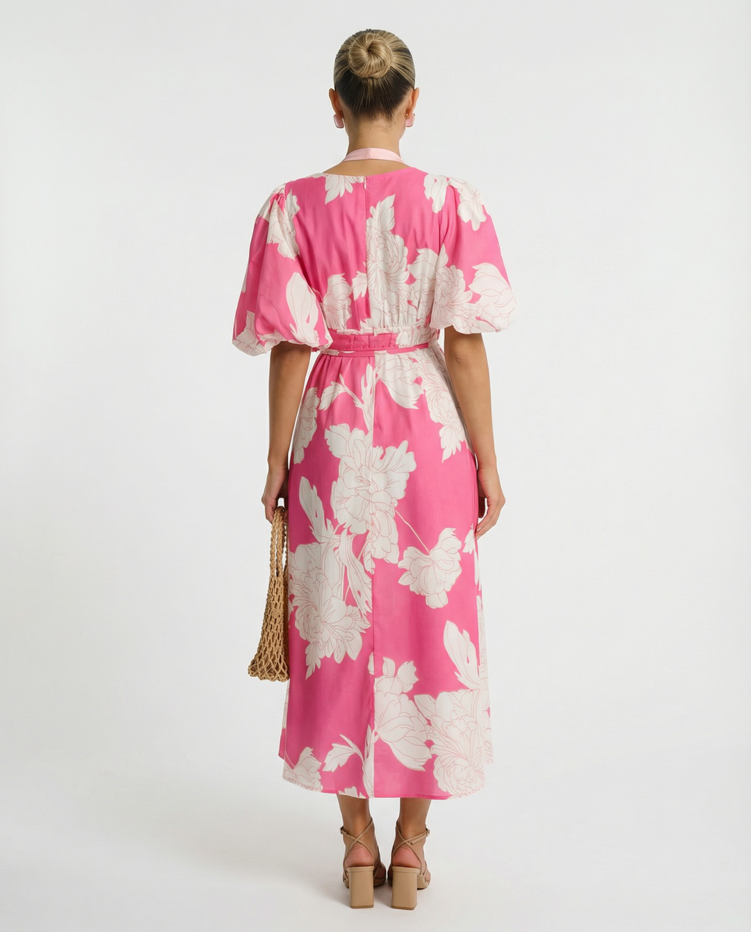 Model wearing a flowing floral midi dress with puff sleeves on a plain background.