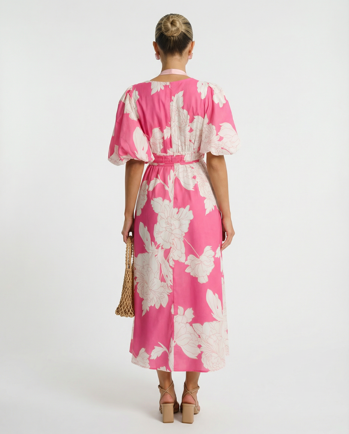 Model wearing a flowing floral midi dress with puff sleeves on a plain background.