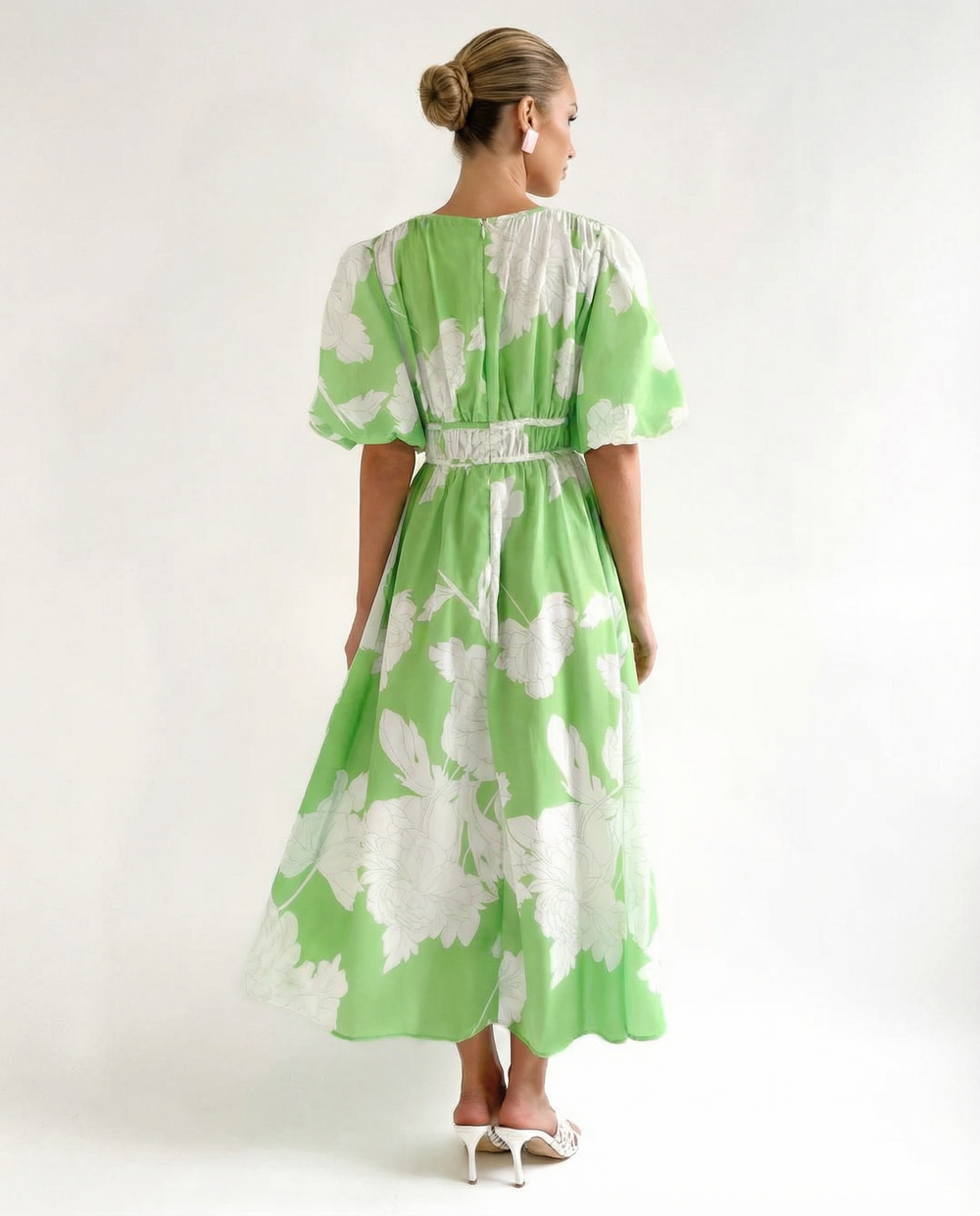 Female model in a green floral midi dress with a V-neckline on a plain background.