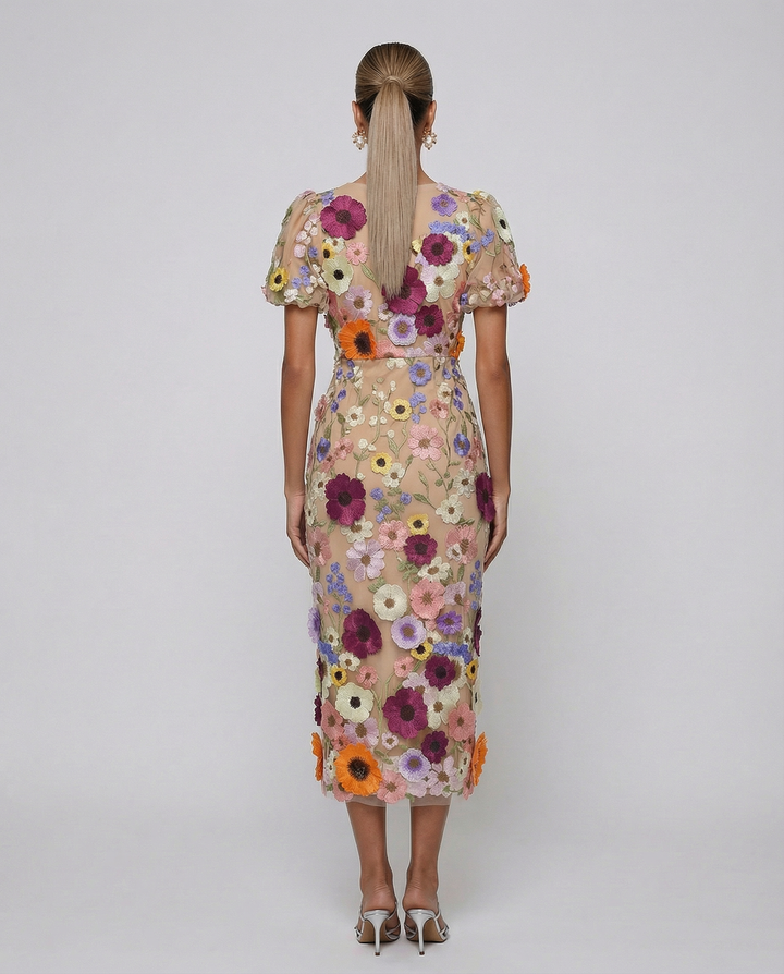 Woman in a V neckline midi dress with floral detailing on a plain background.