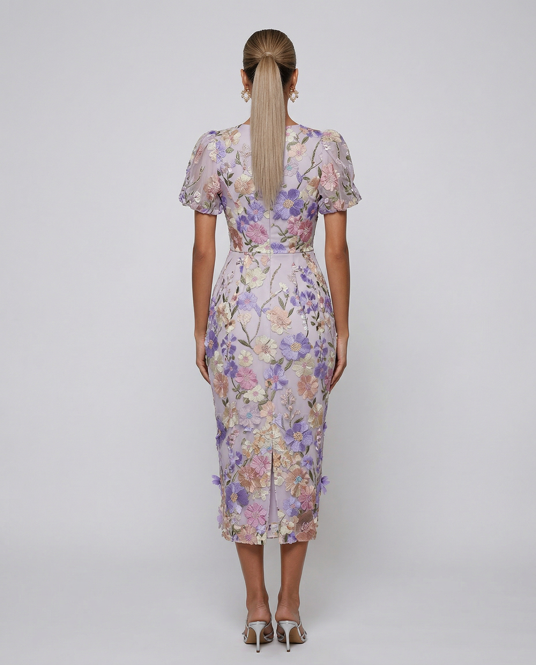 Model wearing a embroidered midi dress on a plain background.
