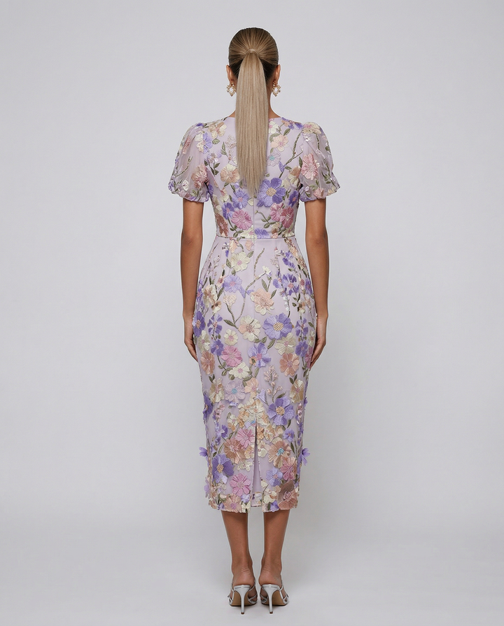 Model wearing a embroidered midi dress on a plain background.