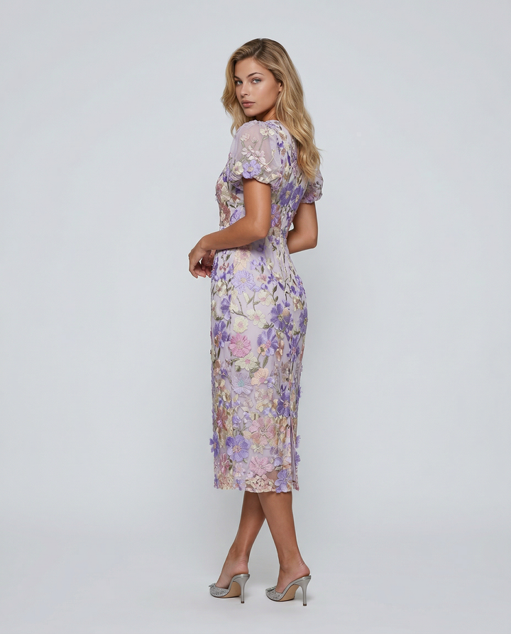 Woman in a purple floral midi dress against a plain background.