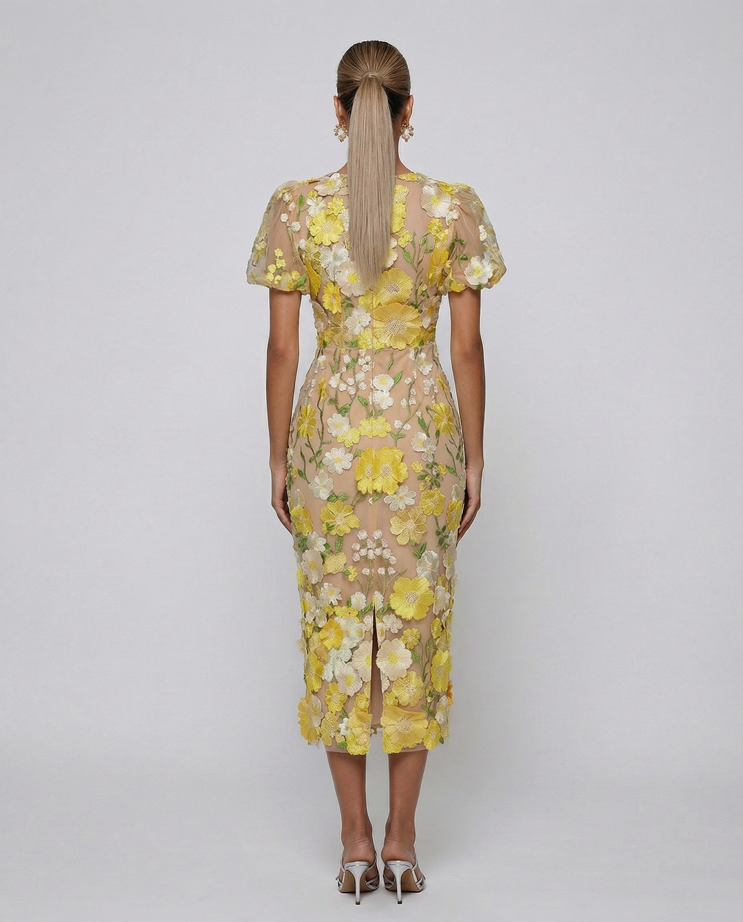 Woman wearing a calf-length floral dress with short sleeves on a plain background.