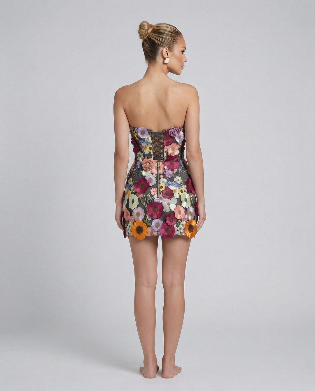 Female model in a fitted floral embroidered tube mini dress on a plain background.