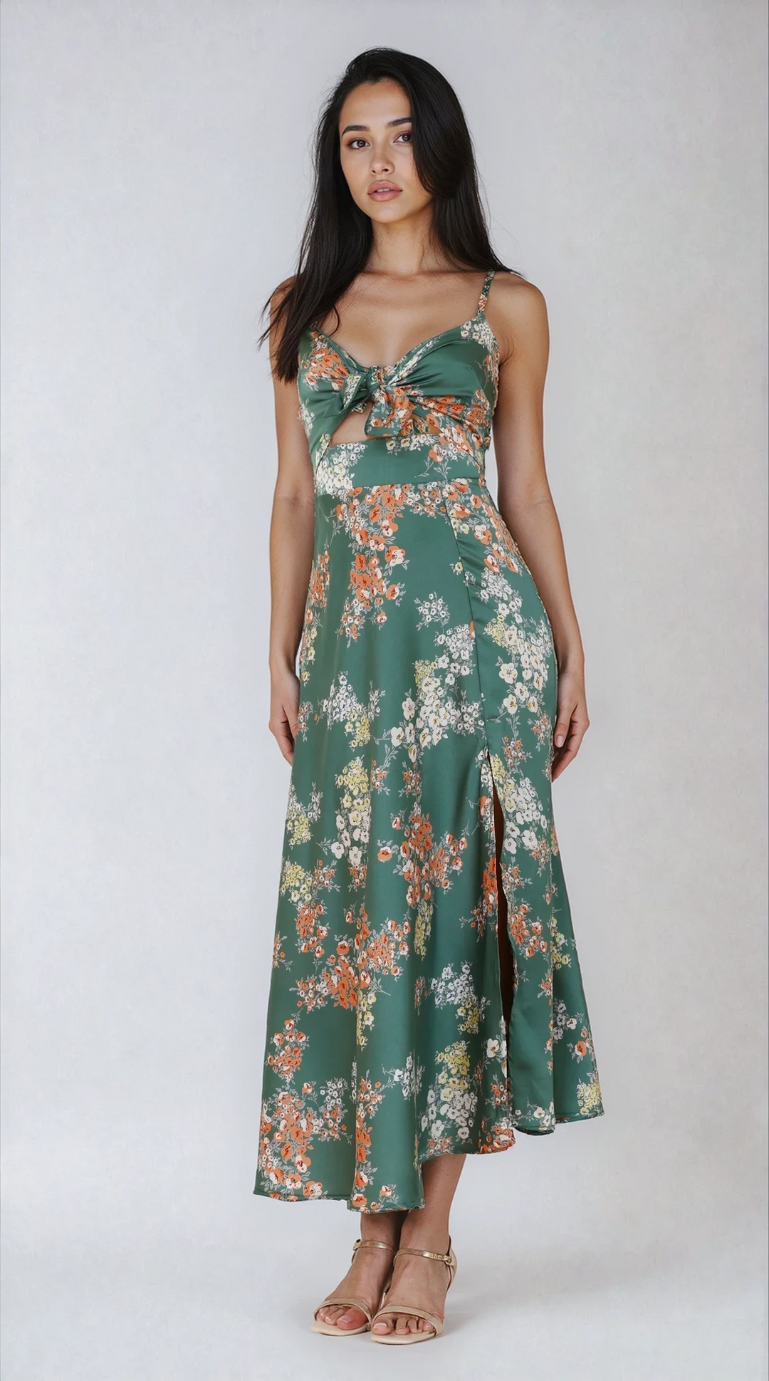 Woman wearing a green floral midi dress with front tie detail on a plain background.