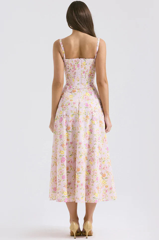 Female model in a pink floral midi dress with a fitted bodice on a plain background.