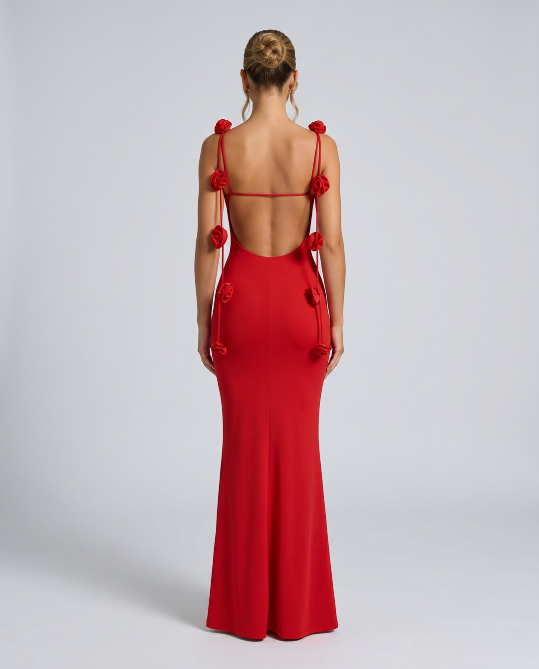 Woman posing in a low back gown with soft floral strap detailing.