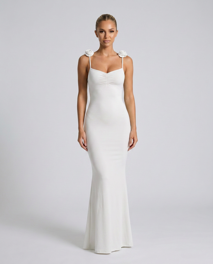 Female model wearing a white maxi gown with slim straps against a plain background.