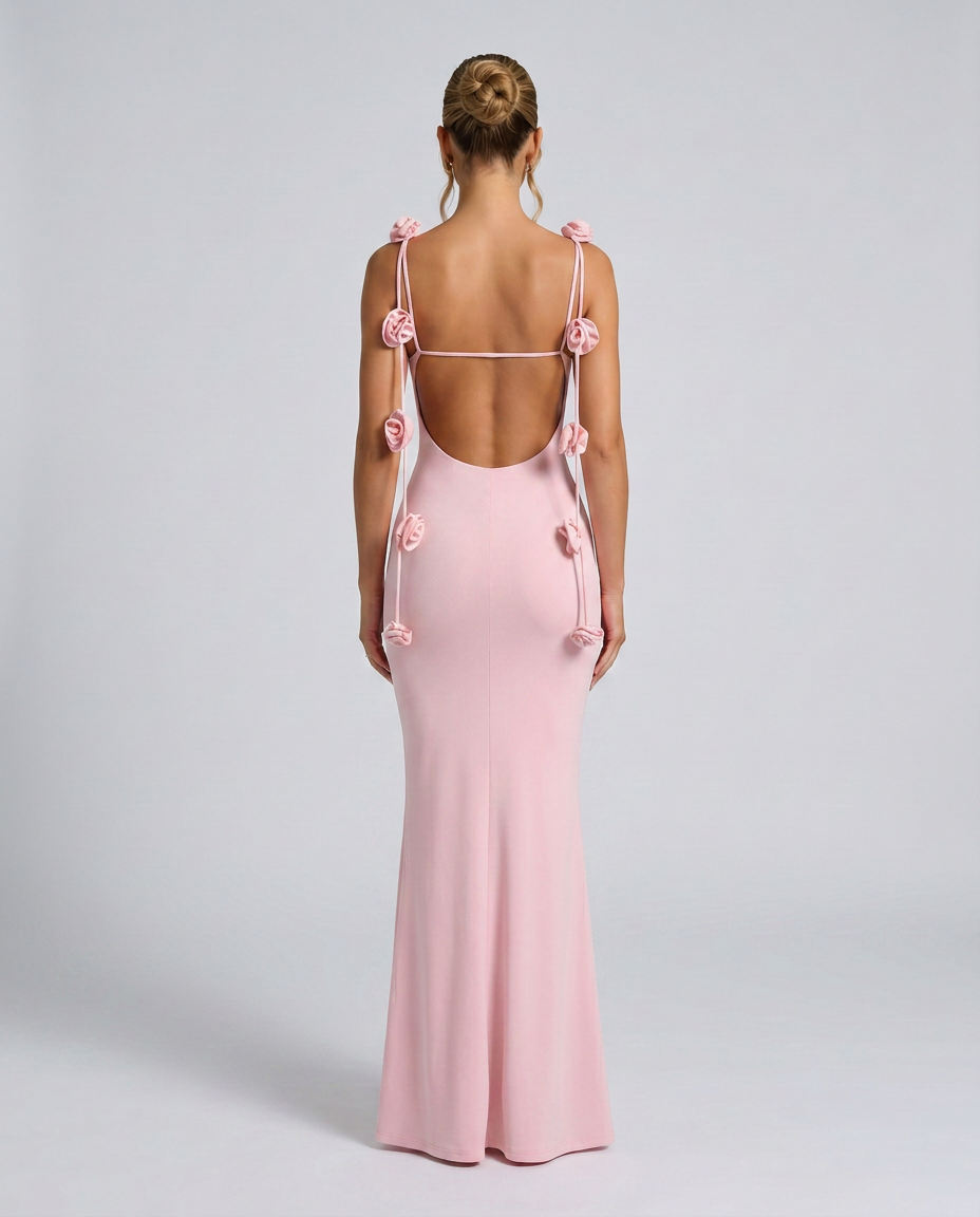 Woman showcasing a pink maxi dress with floral accents on the straps.