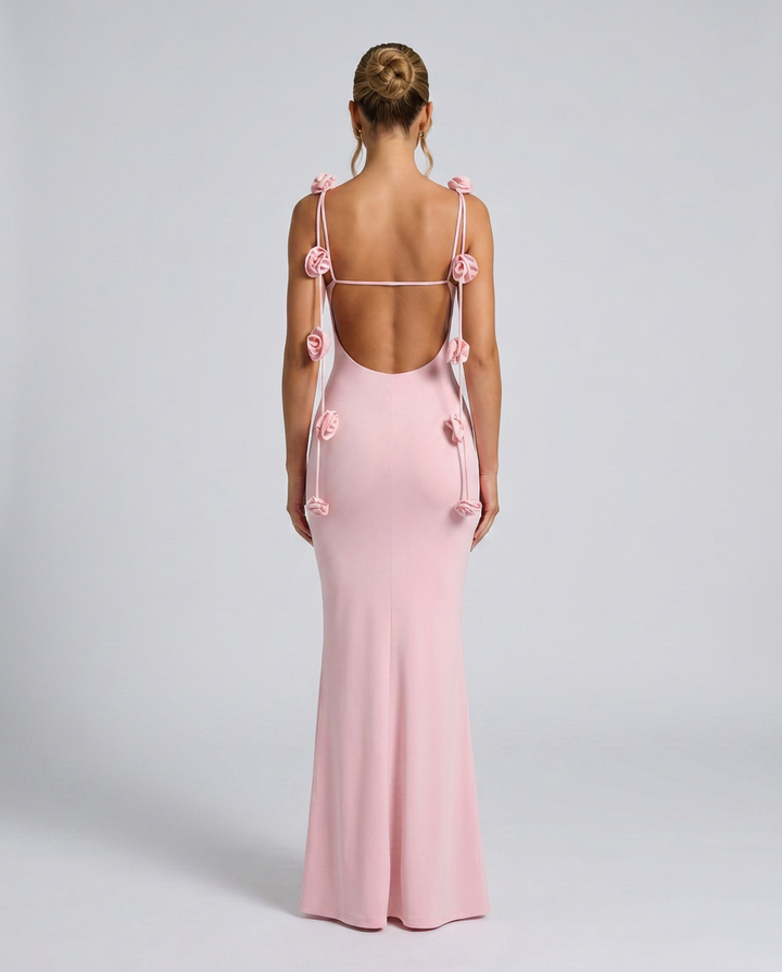 Woman showcasing a pink maxi dress with floral accents on the straps.