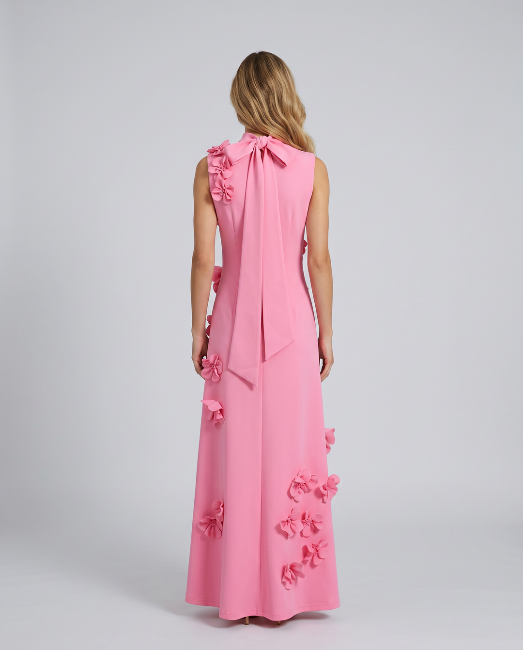 Woman in a high neck floral textured maxi dress on a plain background.