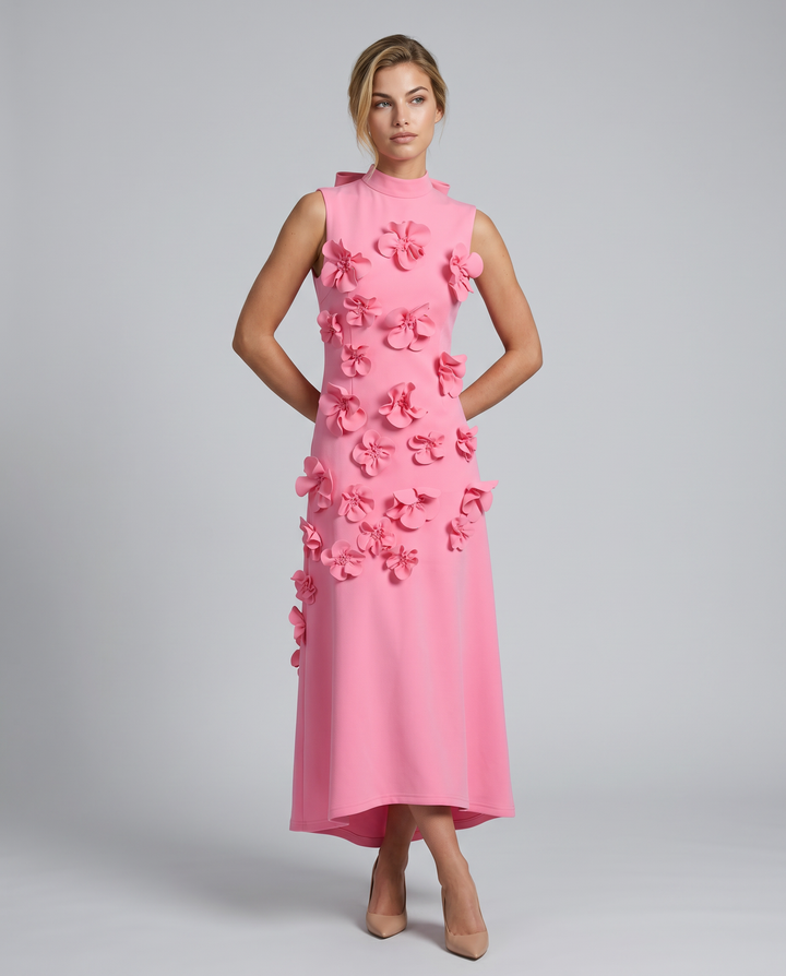 Woman posing in a floral appliqué long dress against a plain background.