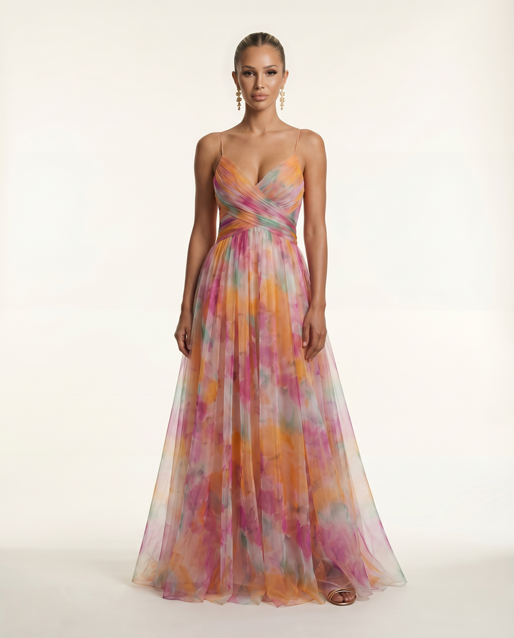 Female model wearing a floral maxi dress with thin straps on a plain background.
