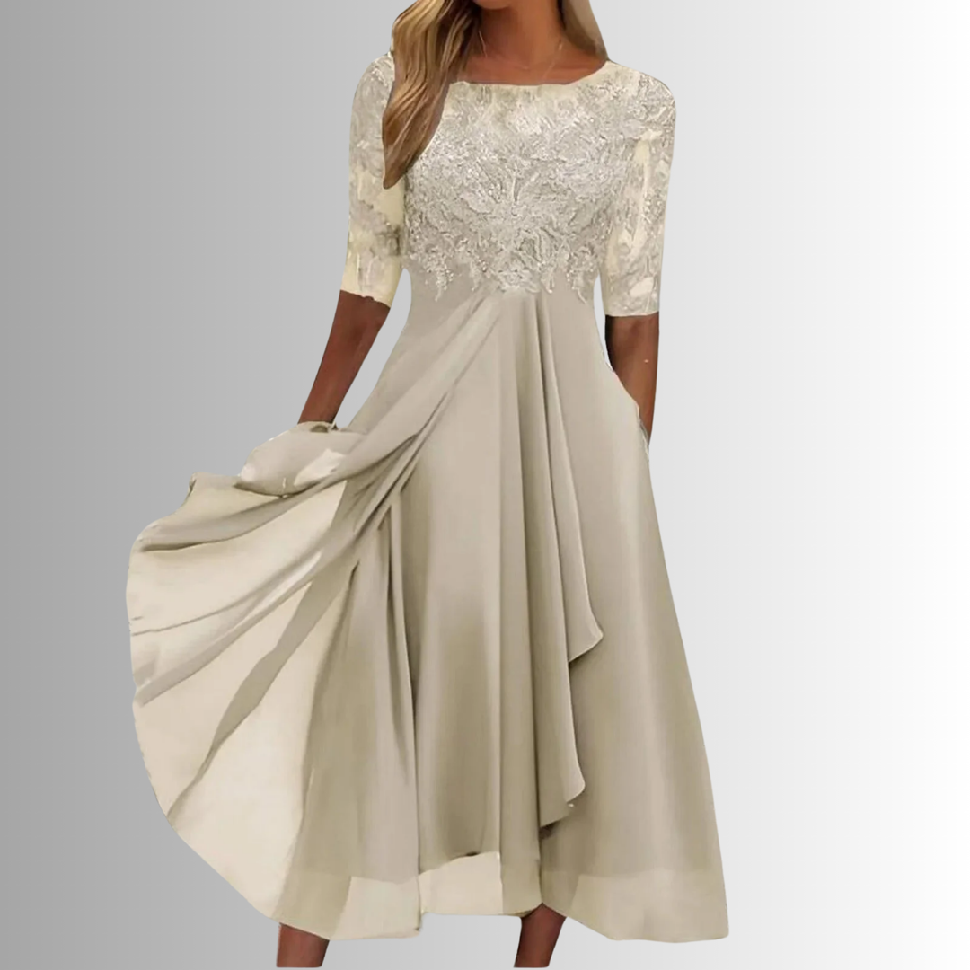 Female model showcasing a flowing lace occasion dress on a plain background