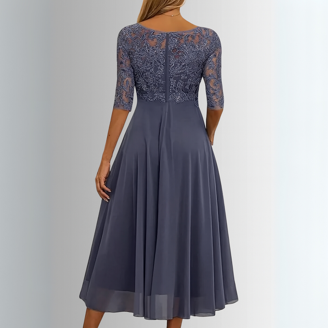 Woman in a feminine lace party dress against a plain background