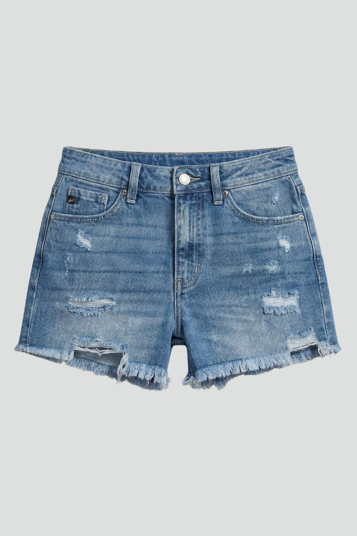 Female model wearing ripped shorts with frayed hems on a plain background.