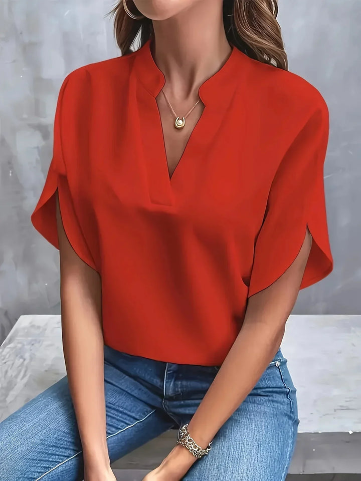 Refined blouse with a model against a plain background presenting a sleek, modern look.