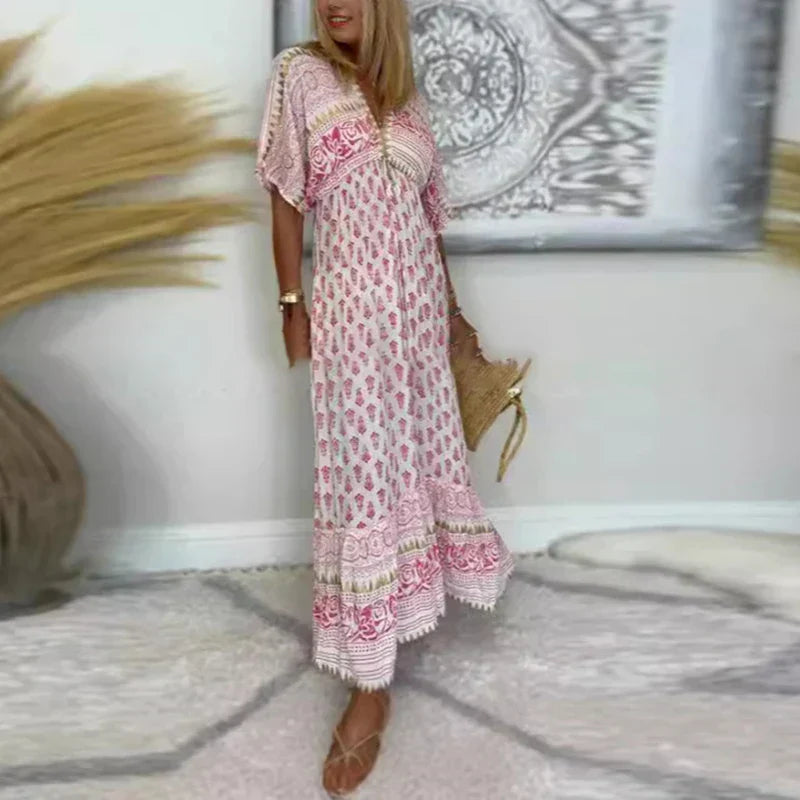 Woman posing in a printed sleeveless maxi dress on a plain background.