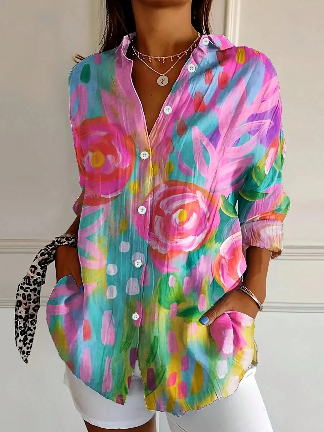 Colourful women’s blouse with playful print shown w/ model against a plain background.