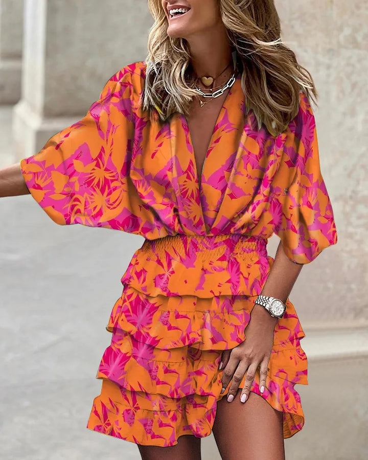 Woman showcasing a vibrant ruffle hem mini dress with bold patterns on a plain background.