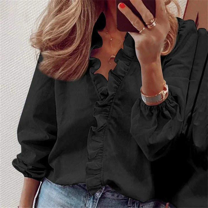 Casual draped blouse with soft ruffles worn by a person in a plain setting.
