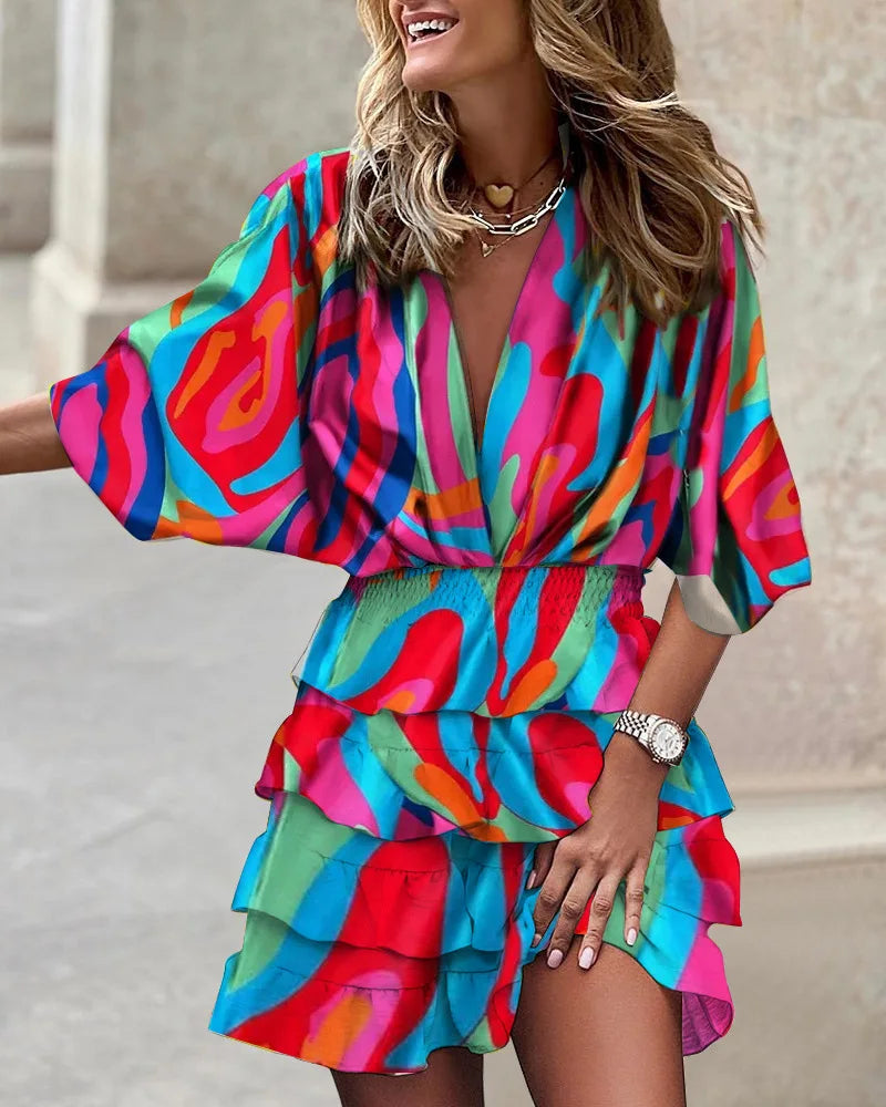 Female model wearing a flowy printed mini dress with tiered skirt against a clean backdrop.