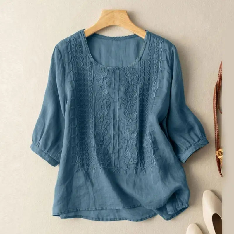 Elegant embroidered blouse displayed on a female figure with clean background.