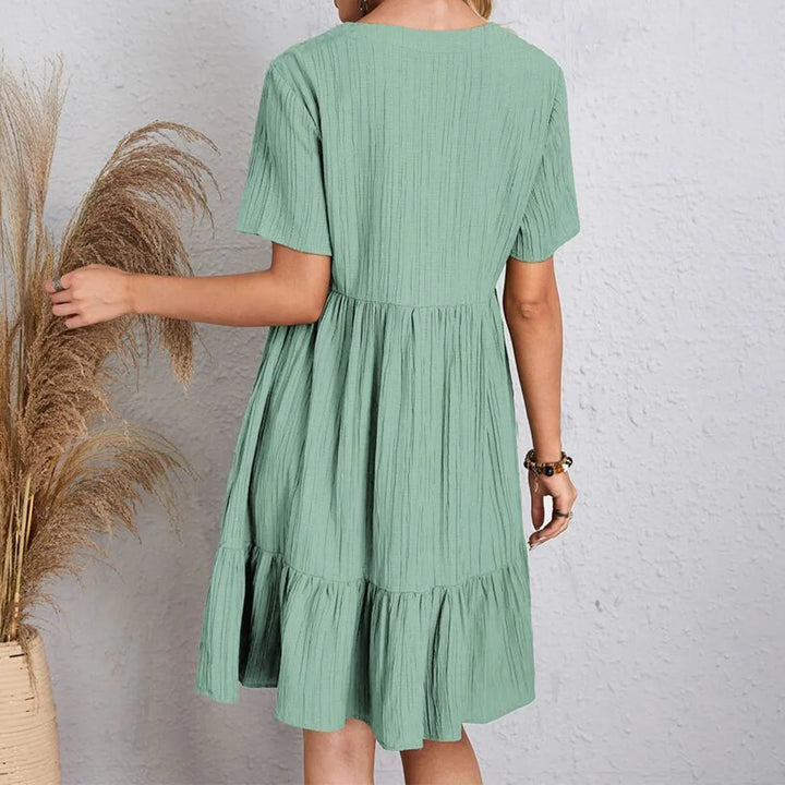 Female model showcasing a casual ruffle hem mini dress on a clean background, back view