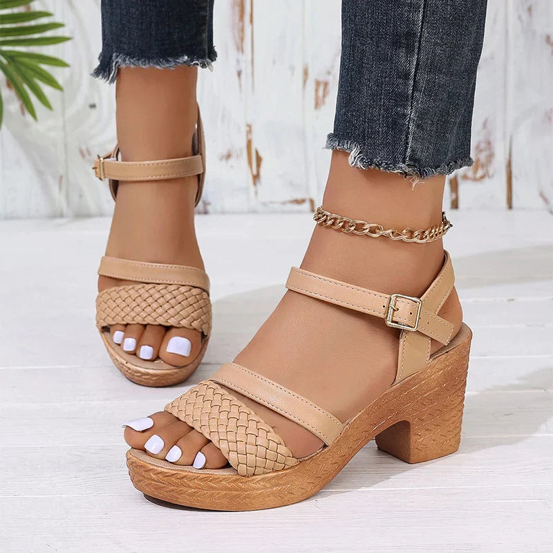 Woman wearing woven platform sandals on feet against a plain background.