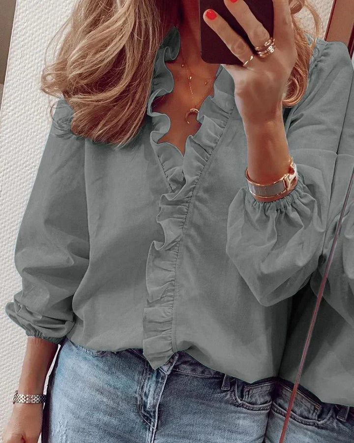 Everyday ruffled top worn by a person in a simple minimal background.