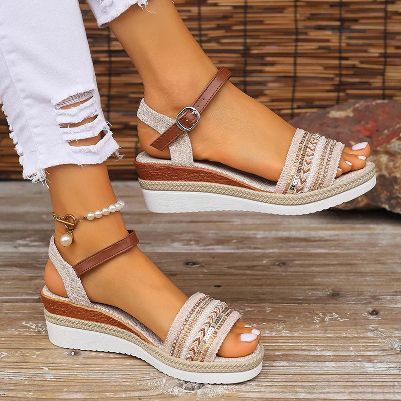 Female feet wearing stylish boho sandals on a clean background