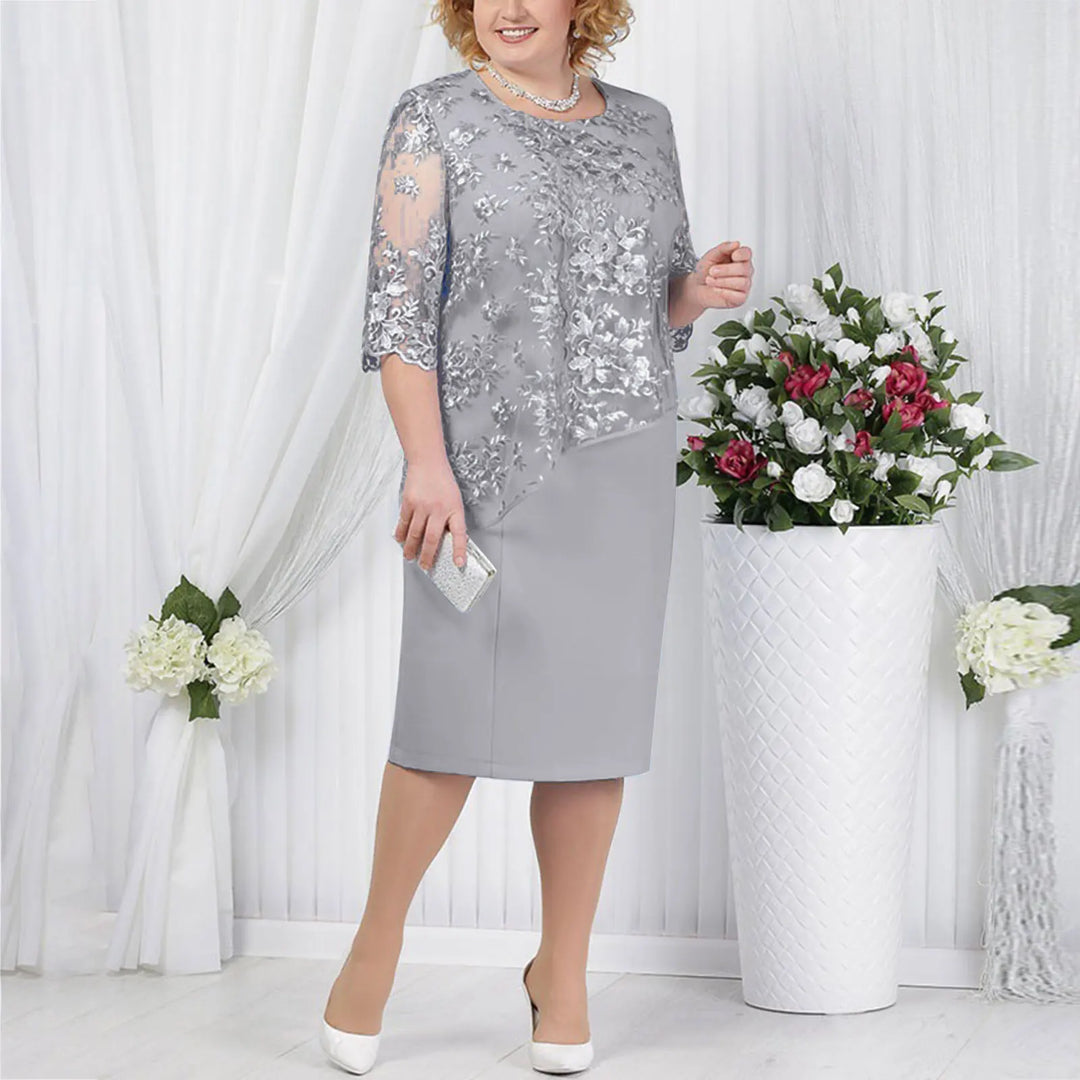 Woman posing in an elegant ruched midi dress with lace sleeves on a plain background.
