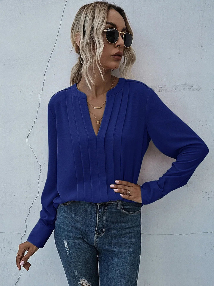 Elegant draped blouse with refined details shown on a person against a clean background.