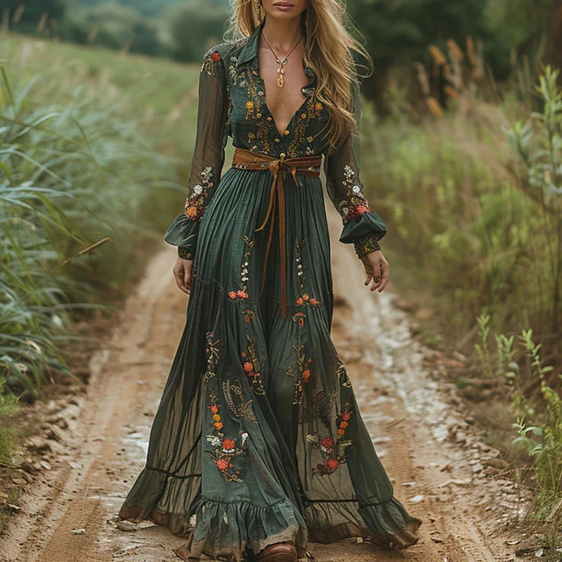 Female wearing a floral maxi dress with pleated details against a nature background.