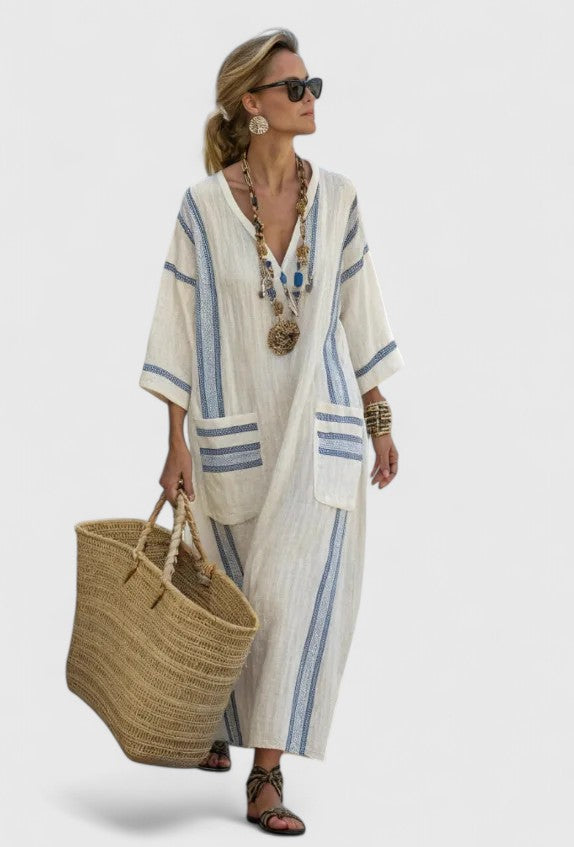  Female model in a breezy striped maxi dress with front pockets on a plain background.