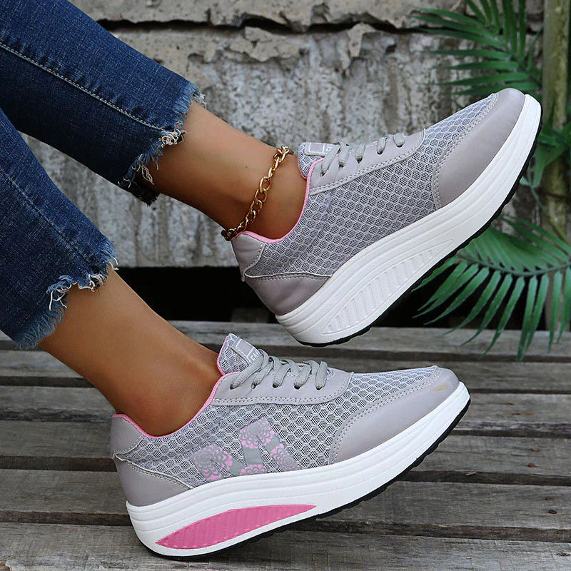 Female model wearing lightweight casual sneakers on a plain background.
