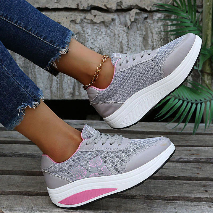 Female model wearing lightweight casual sneakers on a plain background.