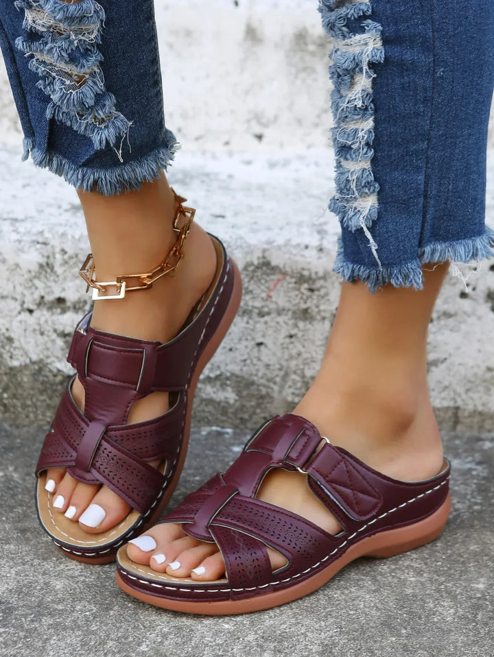Woman posing in lightweight wedge sandals on a plain background