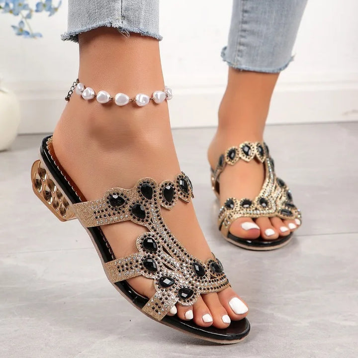 Woman showing dressy sandals with refined details on a clean background.