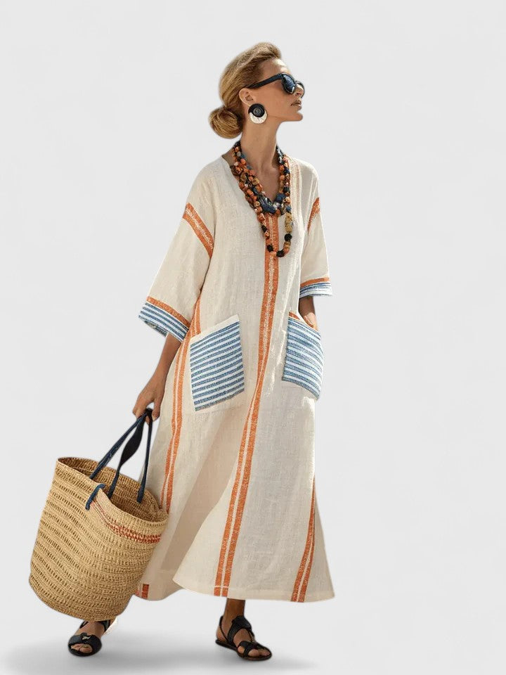   Woman wearing a loose striped kaftan dress with a deep neckline on a plain background.