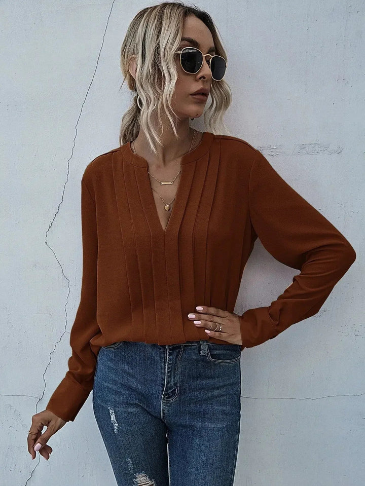 Sophisticated pleated blouse styled on a person with a plain background.