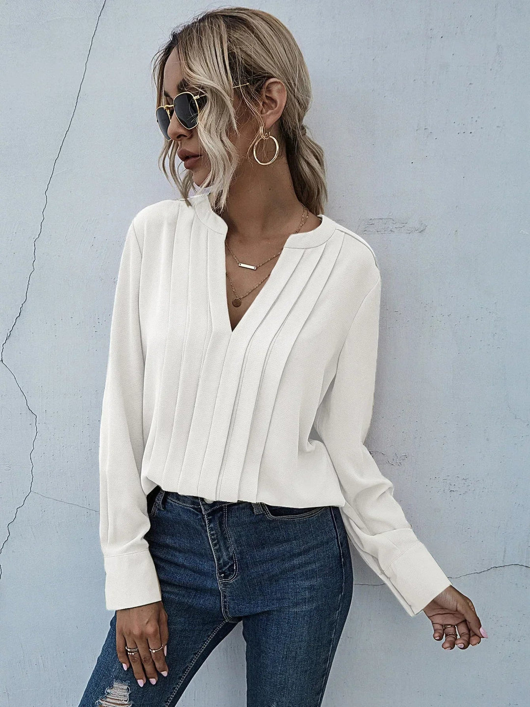 Polished pleated blouse styled on a person against a plain background.