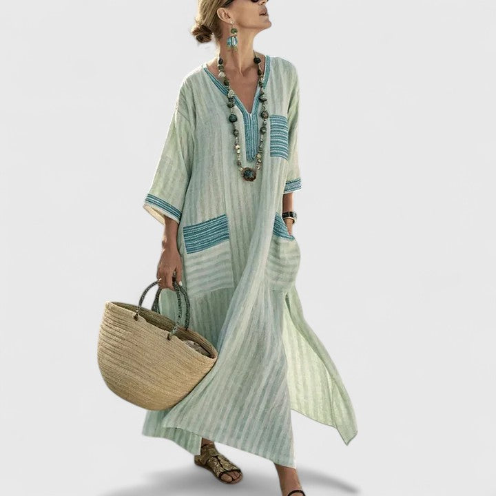 Women’s striped maxi dress on a plain background with V-neck trim, 3/4 sleeves, and front pockets.