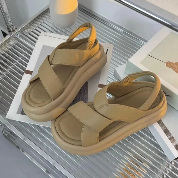 Comfortable women’s sandals with wedge lift and textured outsole on a plain background.