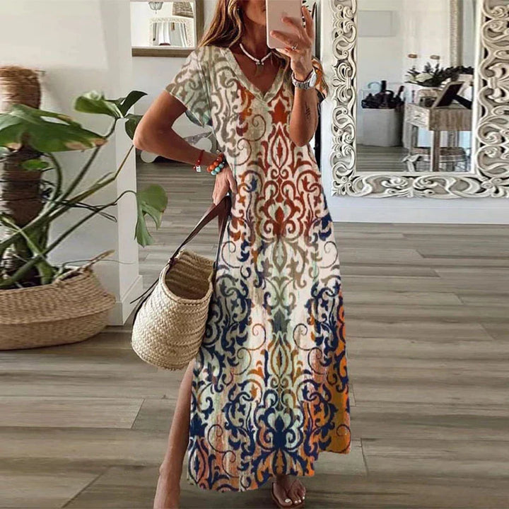 Female wearing a flowing boho print maxi dress against a plain background.