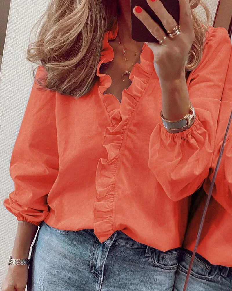 Flowing everyday blouse with ruffles styled on a person in a minimal backdrop.