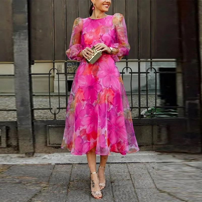 Female model wearing a floral midi wedding guest dress on a plain background.